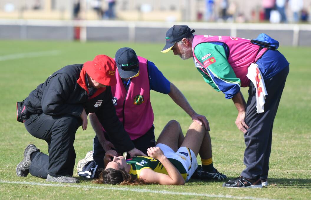 Jasper Gunn in the hands of trainers after copping a high hit in the first quarter.