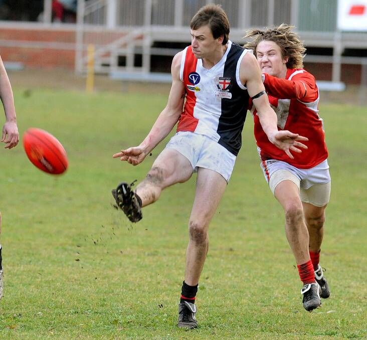 A young Chris Oliver gets a kick away from Taylors Lake's Deek Roberts.