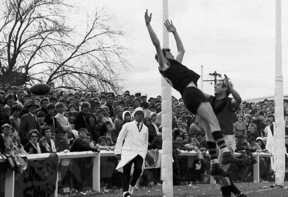 Two players fly for the ball in front of a massive crowd at the 1969 grand final.