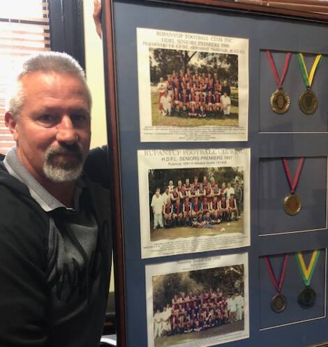 Paul Brooks with his framed memorabilia. Pictured are the three premiership-winning sides from 1996-98 as well as his premiership medals and the league best and fairest medals he won in 1996 and 1998.