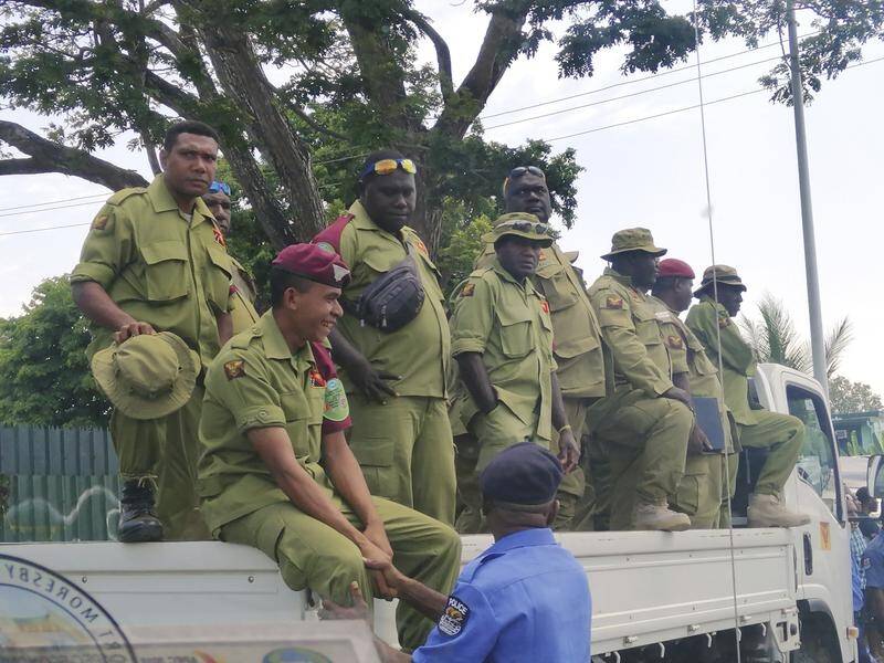Security personnel on the back of a truck wait to be paid in Port Moresby.