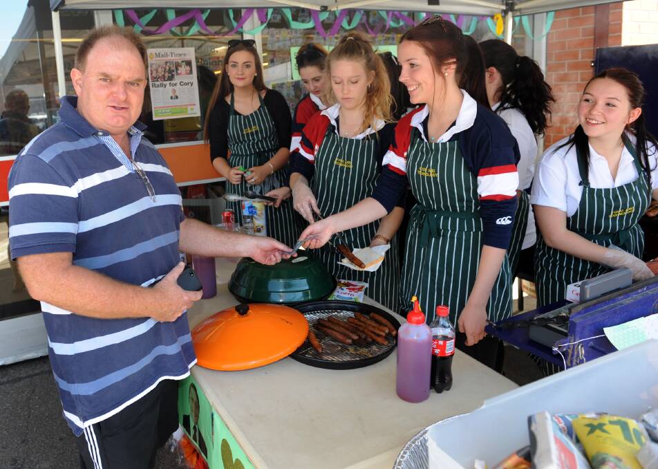 St Brigids College principal Peter Gutteridge buys a sausage at Rally For Cory. 