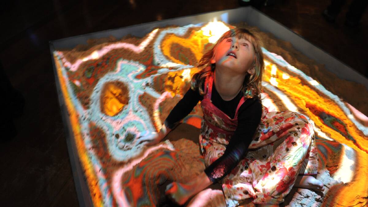 LAYERS OF TIME: Ruby Sathratine digs for fossils in the sandpit at a Museum of Lands Past during the launch of the Art is... festival at the weekend. Picture: PAUL CARRACHER