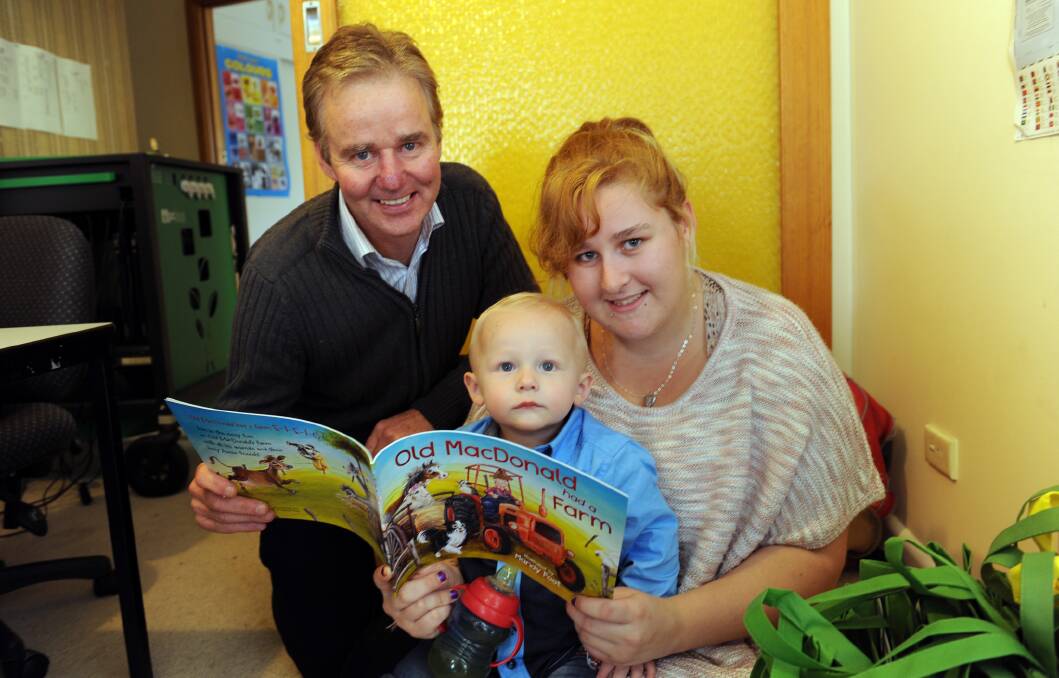 LET’S READ: Wimmera Southern Mallee Local Learning and Employment Network executive officer Tim Shaw presents a book to young mum Kezra Hansen and son Tremayne. Picture: PAUL CARRACHER