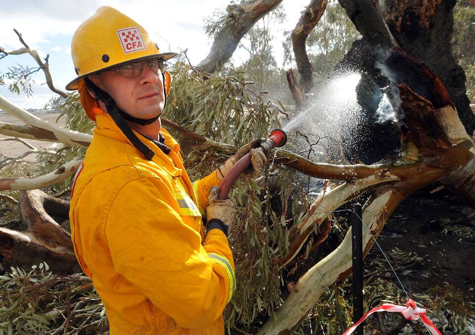 BLACK SATURDAY: Fire-fighter Shane Sanders douses a flaming log with water.