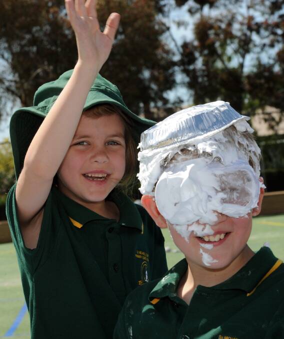 Claire Longstaff, 6, covers her brother Shaun, 10, in cream pie at Ss Michael and John s Primary School s Mission Day on Friday. 	 Picture: PAUL CARRACHER